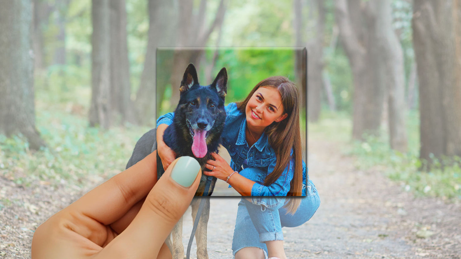 Hand holding a magnet photo of a woman with a dog in a forest setting